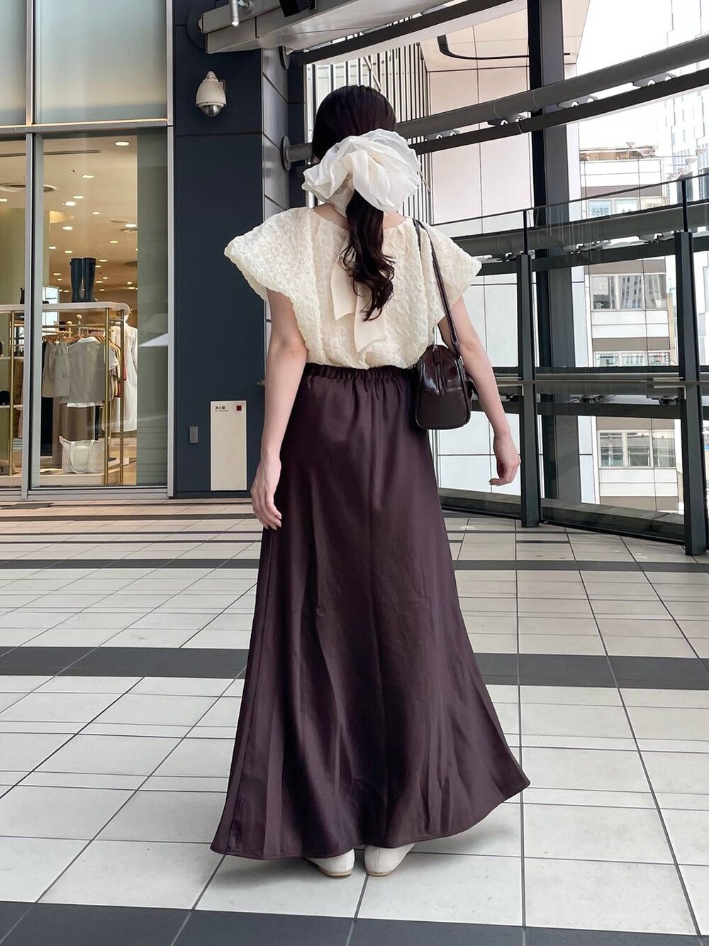 ブラウン系のスカート、ベージュ系のシャツ/ブラウス、ベージュ系のシュシュを着用したレディースの夏コーディネートの3枚目の写真