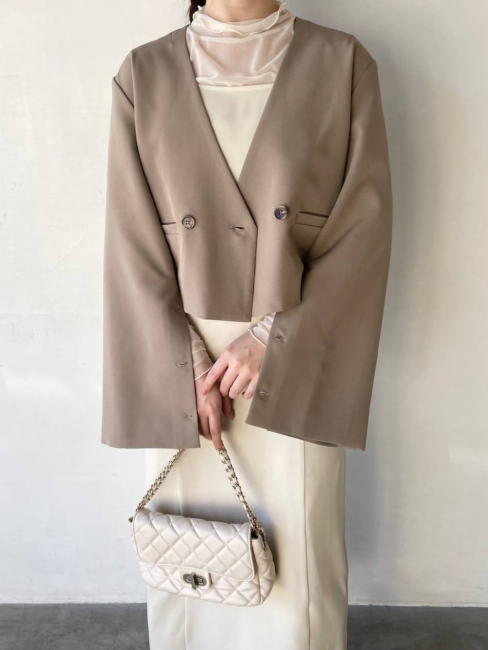 ホワイト系のドレス、ホワイト系のショルダーバッグ、ベージュ系のパンプスを着用したレディースの冬コーディネートの4枚目の写真