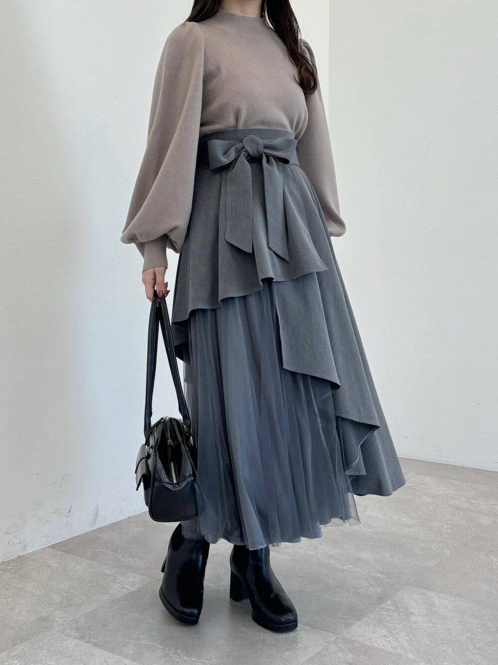 ブラック系のブーツ、ブラック系のハンドバッグ、ブラウン系のニット/セーターを着用したレディースの冬コーディネートの5枚目の写真