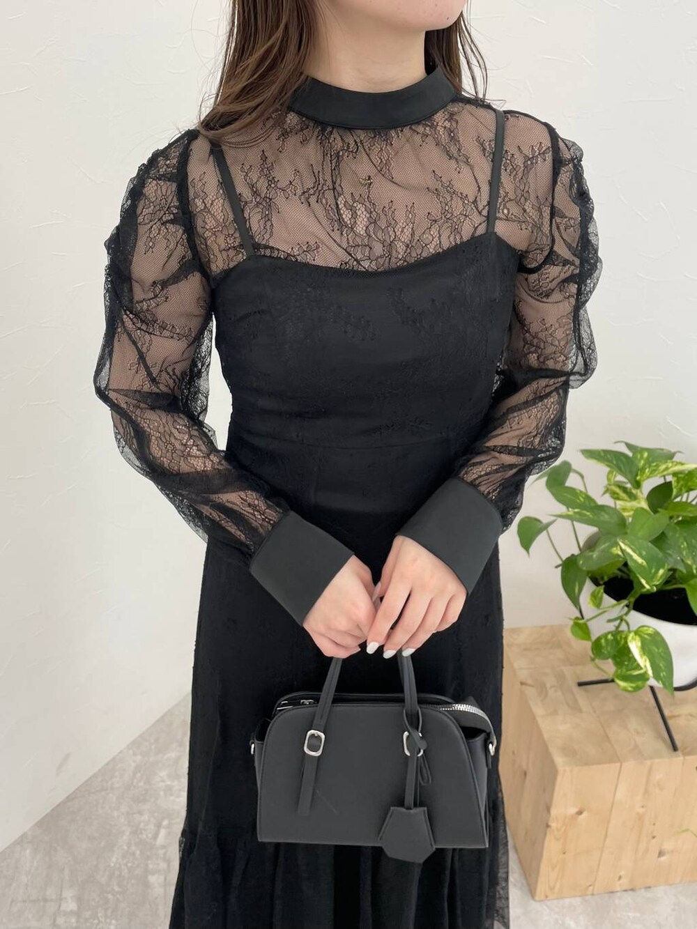 ブラック系のパンプス、ブラック系のボストンバッグ、ブラック系のドレスを着用したレディースの冬コーディネートの3枚目の写真