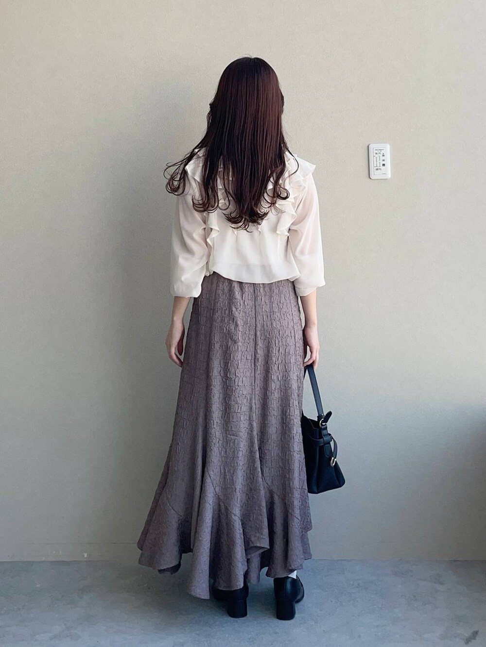 ブラック系のショルダーバッグ、ブラウン系のスカート、ホワイト系のシャツ/ブラウスを着用したレディースの冬コーディネートの2枚目の写真