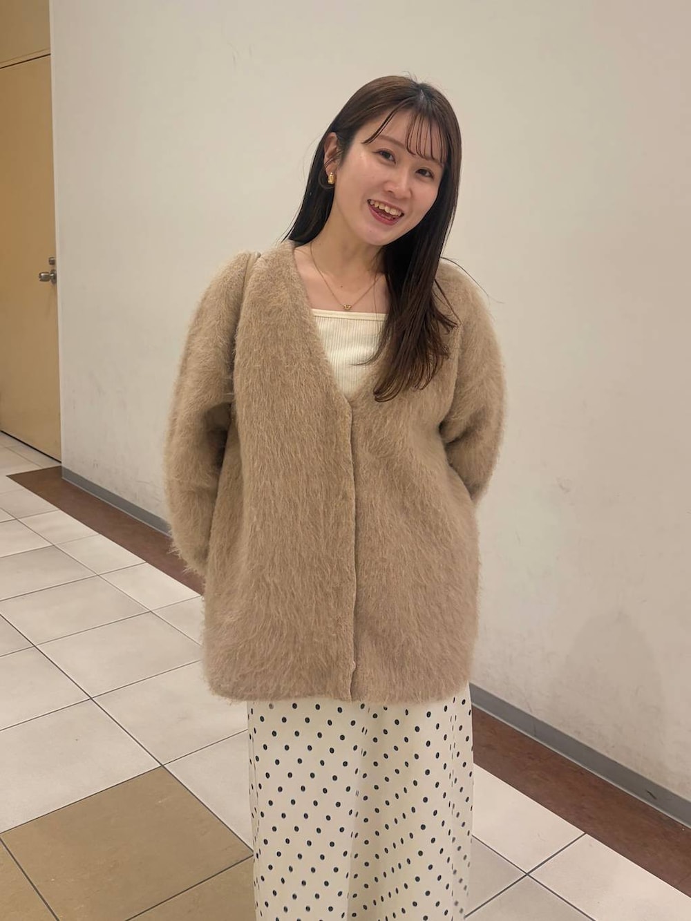 ホワイト系のスカート、ベージュ系のカーディガン/ボレロ、ゴールド系のボストンバッグを着用したレディースの冬コーディネートの4枚目の写真