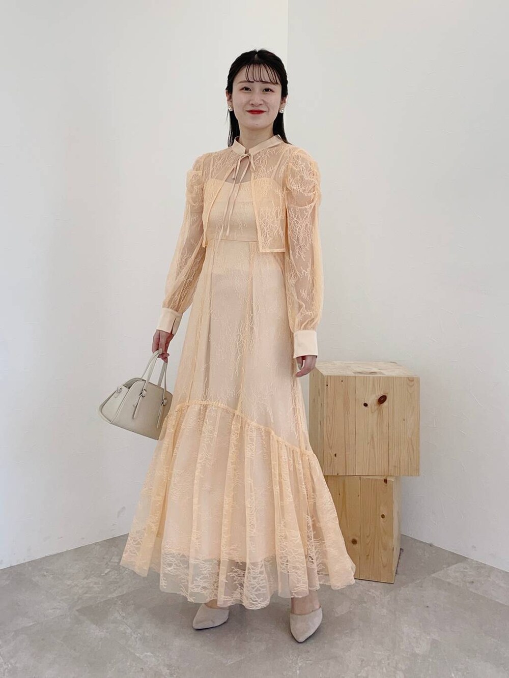 グレー系のパンプス、ホワイト系のボストンバッグ、ホワイト系のチェスターコートを着用したレディースの秋コーディネートの3枚目の写真