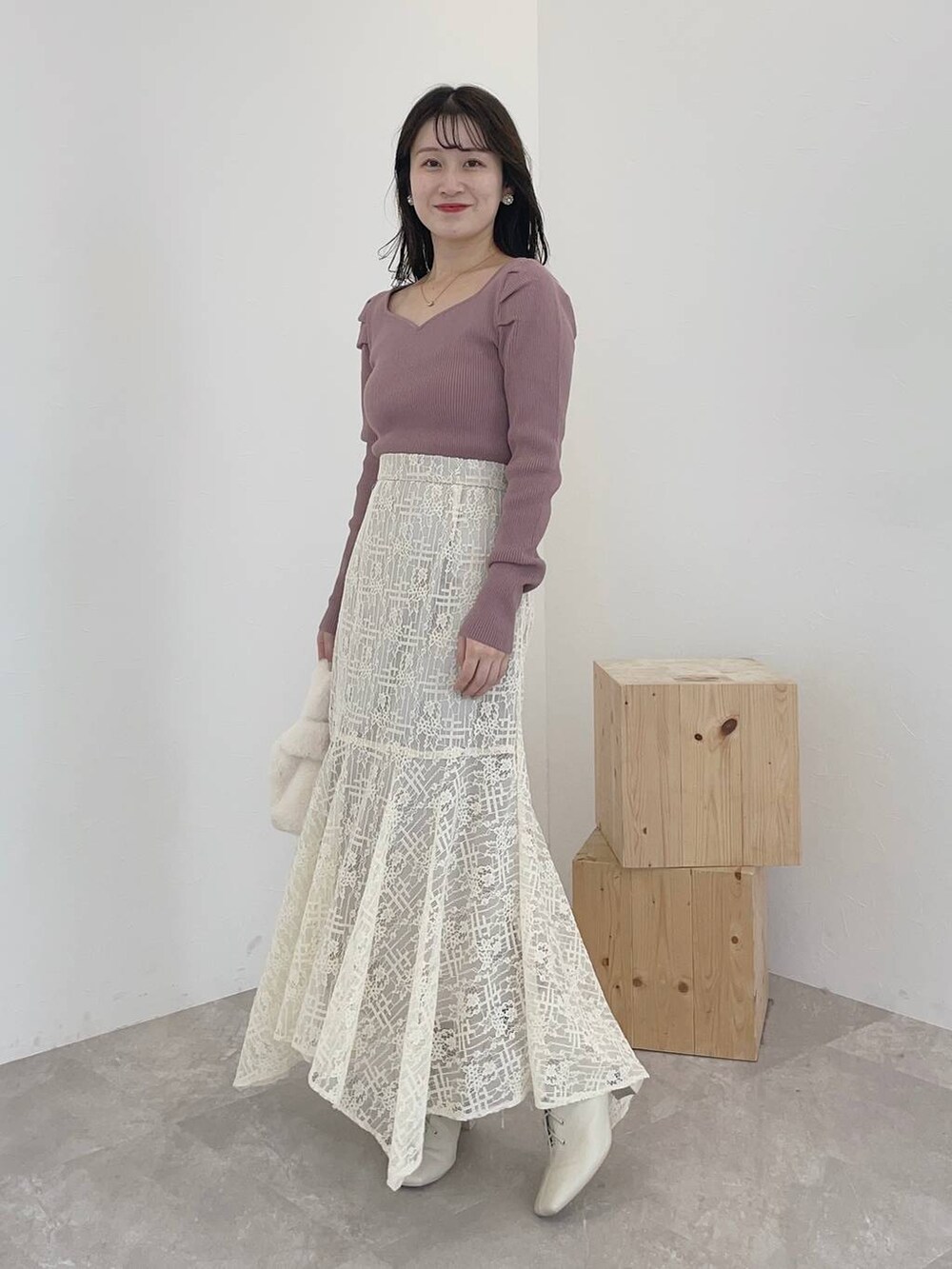 ホワイト系のブーツ、ホワイト系のスカート、ホワイト系のハンドバッグを着用したレディースの秋コーディネートの3枚目の写真