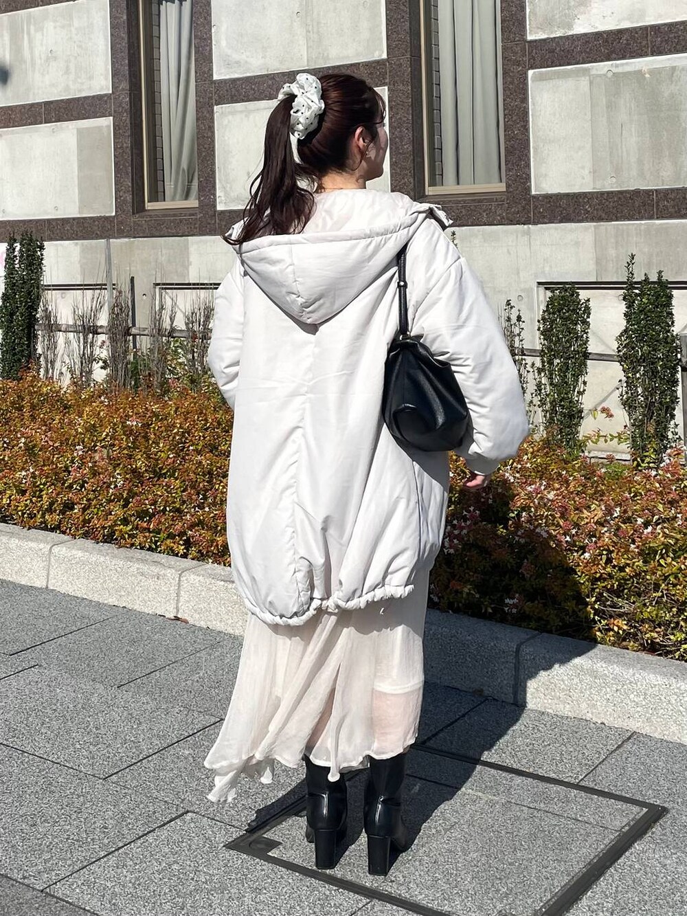 レッド系のニット/セーター、ホワイト系のブルゾン、ホワイト系のスカートを着用したレディースの秋コーディネートの2枚目の写真