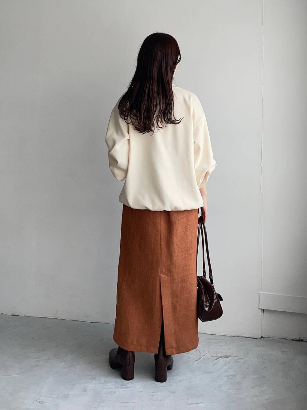 ブラウン系のブーツ、オレンジ系のスカート、ホワイト系のスウェットを着用したレディースの秋コーディネートの2枚目の写真