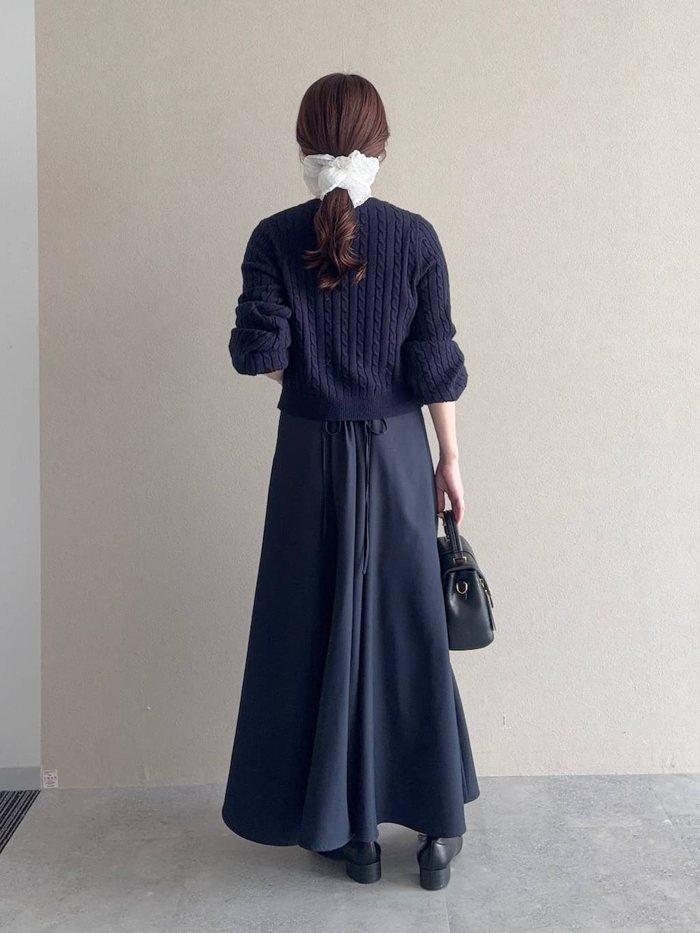 ブラック系のローファー、ブラック系のショルダーバッグ、ブルー系のワンピースを着用したレディースの冬コーディネートの2枚目の写真