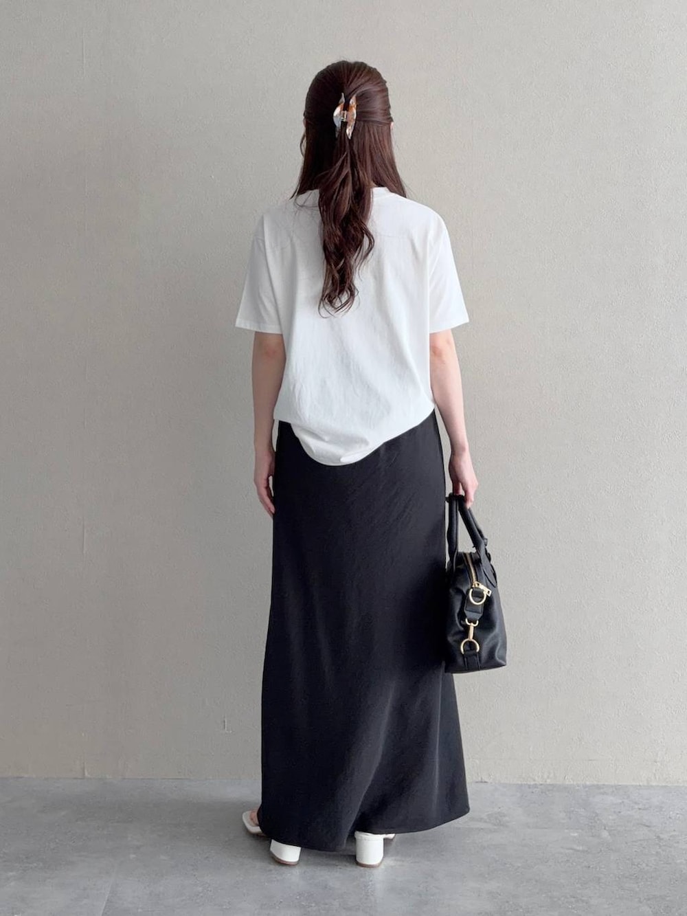 ブラック系のボストンバッグ、ブラック系のスカート、ホワイト系のTシャツ/カットソーを着用したレディースの夏コーディネートの2枚目の写真