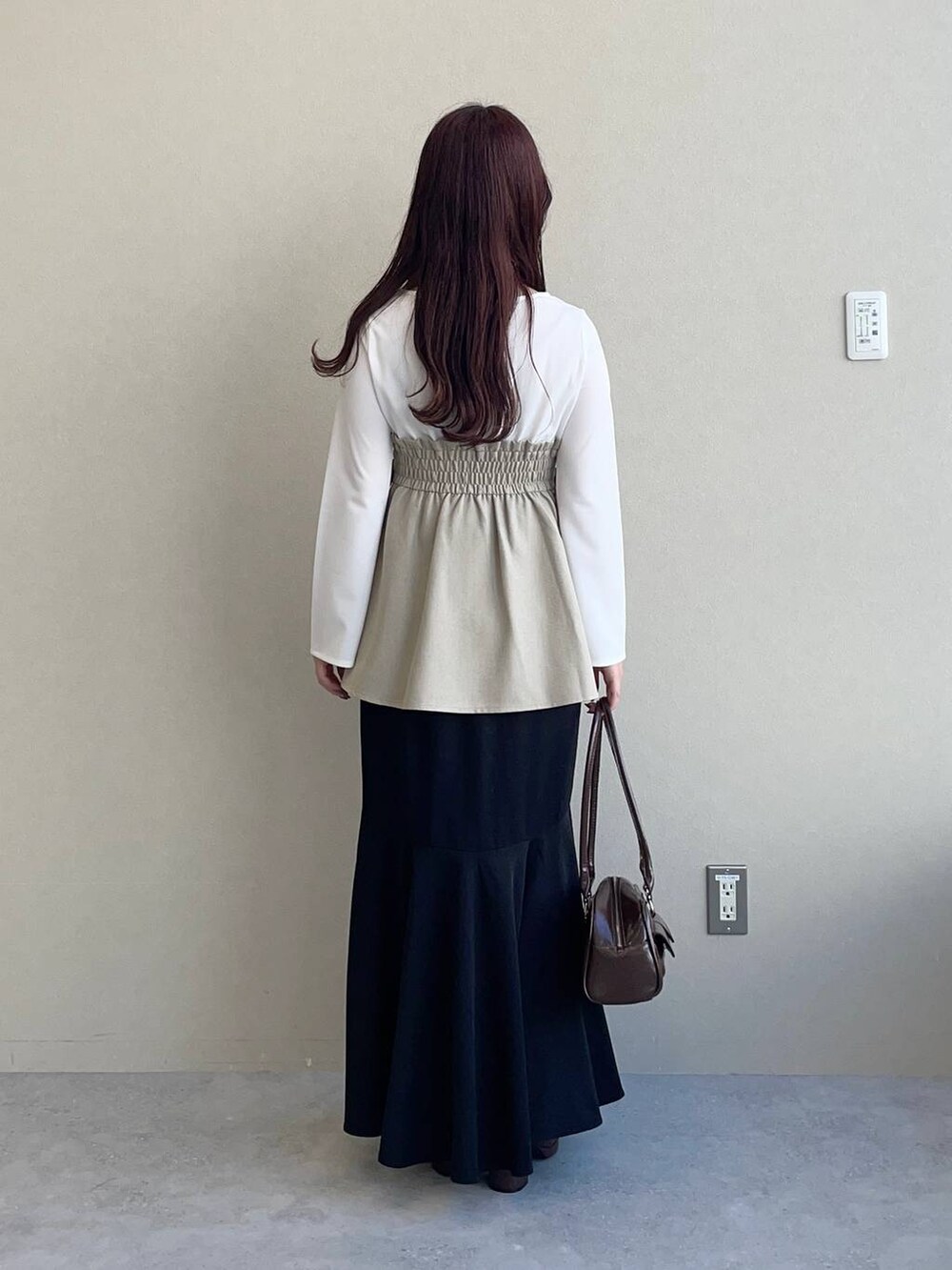 ブラウン系のブーツ、ベージュ系のTシャツ/カットソー、ブラック系のスカートを着用したレディースの冬コーディネートの2枚目の写真