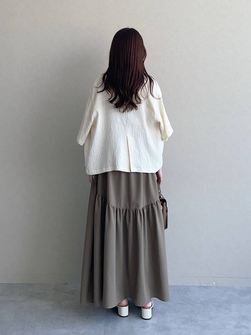 ホワイト系のテーラードジャケット、ブラウン系のショルダーバッグ、ホワイト系のタンクトップを着用したレディースの夏コーディネートの2枚目の写真