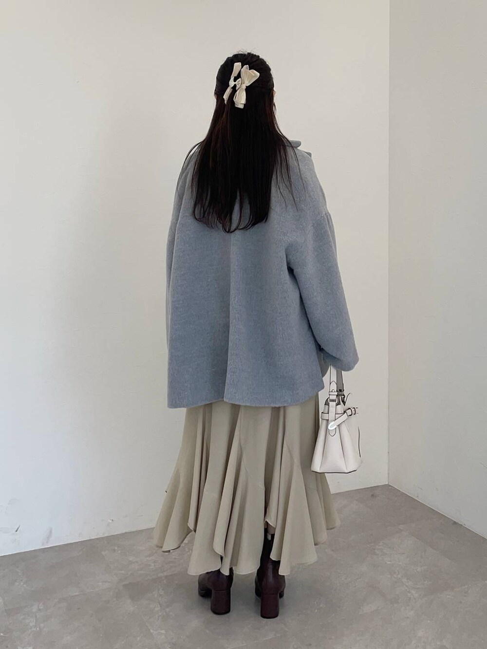 ホワイト系のショルダーバッグ、ブラウン系のブーツ、ホワイト系のニット/セーターを着用したレディースの冬コーディネートの2枚目の写真