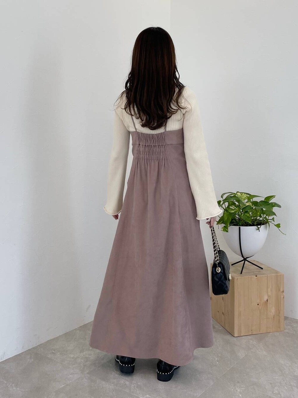 ピンク系のワンピース、ブラック系のショルダーバッグ、ホワイト系のニット/セーターを着用したレディースの冬コーディネートの2枚目の写真