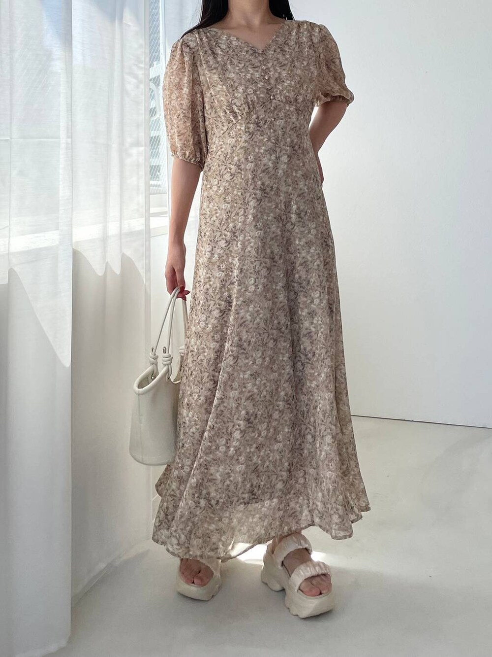 ホワイト系のハンドバッグ、ホワイト系のサンダル、ベージュ系のワンピースを着用したレディースの夏コーディネートの4枚目の写真