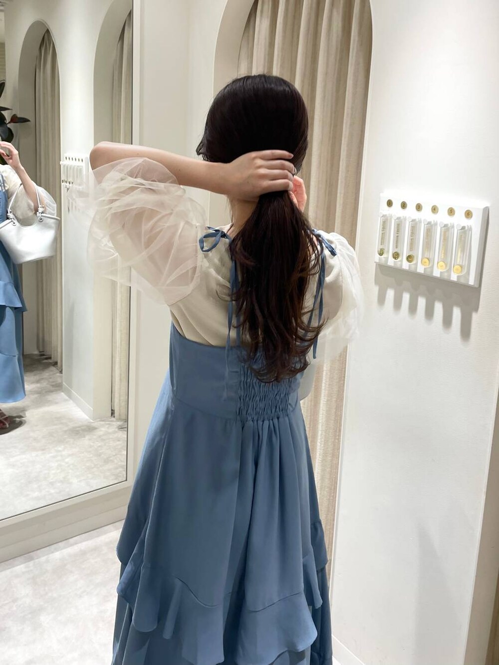 シルバー系のハンドバッグ、ホワイト系のサンダル、ブルー系のワンピースを着用したレディースの春コーディネートの3枚目の写真