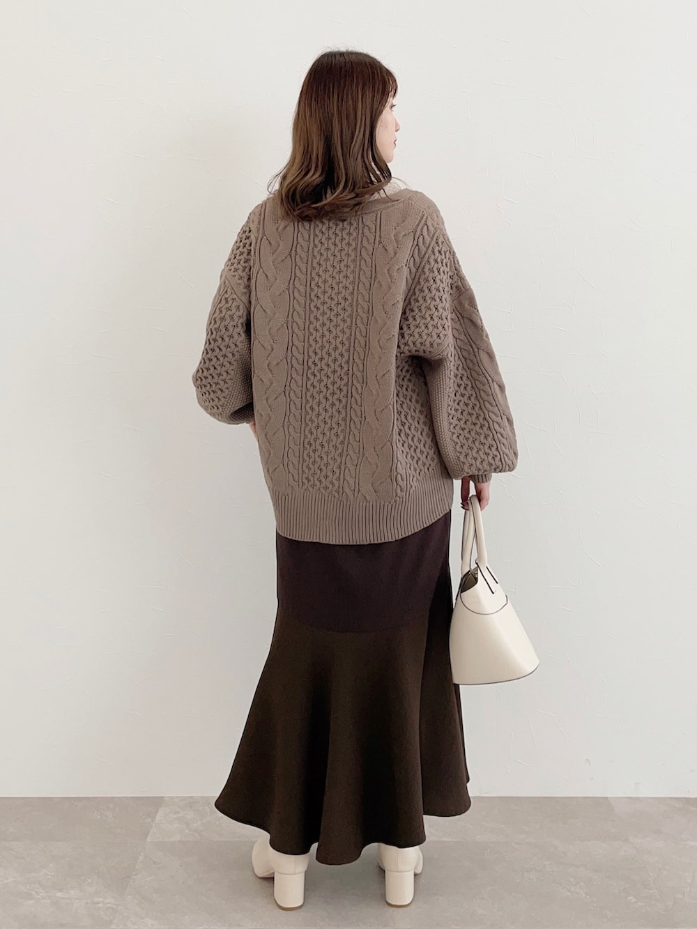 ブラウン系のカーディガン/ボレロ、ベージュ系のTシャツ/カットソー、ホワイト系のショルダーバッグを着用したレディースの秋コーディネートの2枚目の写真