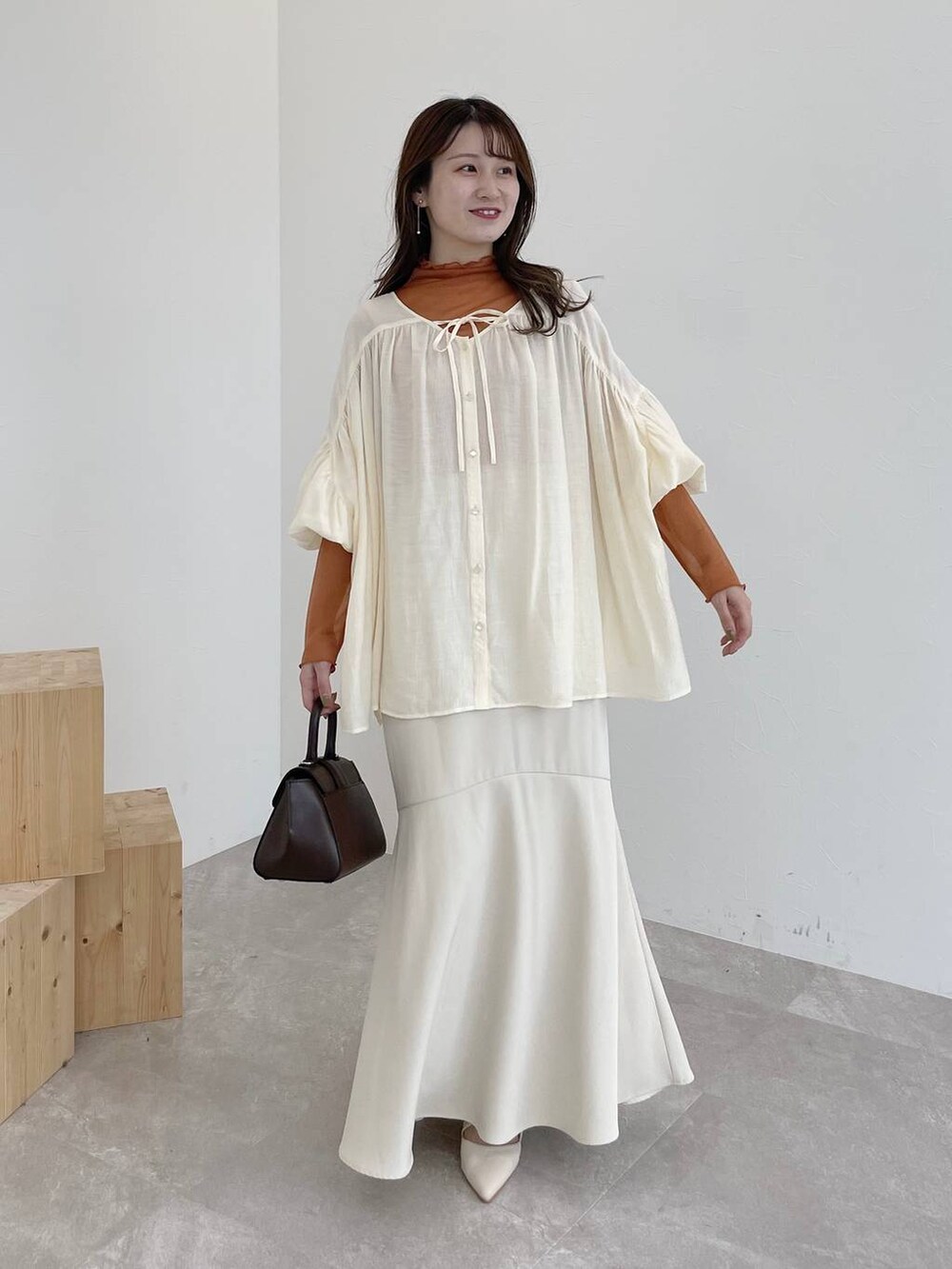 ブラウン系のハンドバッグ、ホワイト系のシャツ/ブラウス、ホワイト系のスカートを着用したレディースの夏コーディネートの2枚目の写真