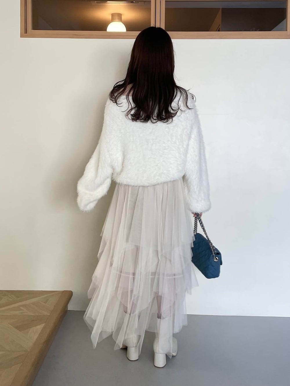 ブラック系のその他アウター、ホワイト系のブーツ、ホワイト系のスカートを着用したレディースの冬コーディネートの5枚目の写真