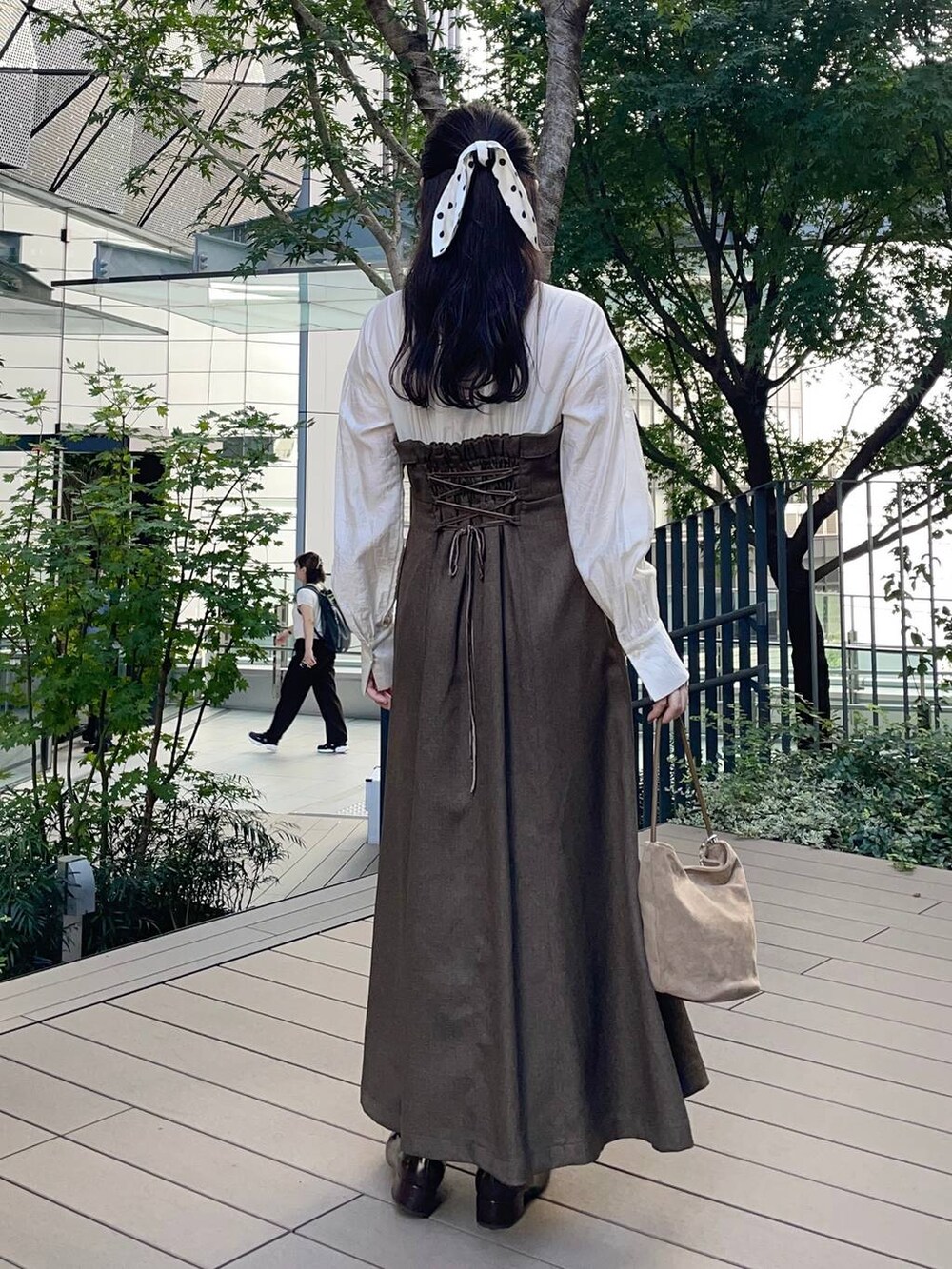 ブラウン系のワンピース、ベージュ系のハンドバッグ、ベージュ系のキーホルダーを着用したレディースの秋コーディネートの2枚目の写真