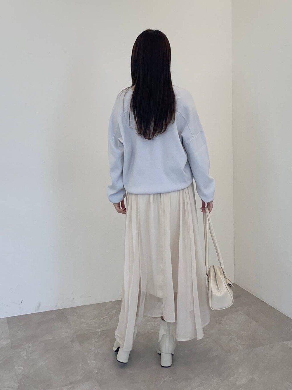 ホワイト系のブーツ、グレー系のニット/セーター、ホワイト系のハンドバッグを着用したレディースの冬コーディネートの2枚目の写真