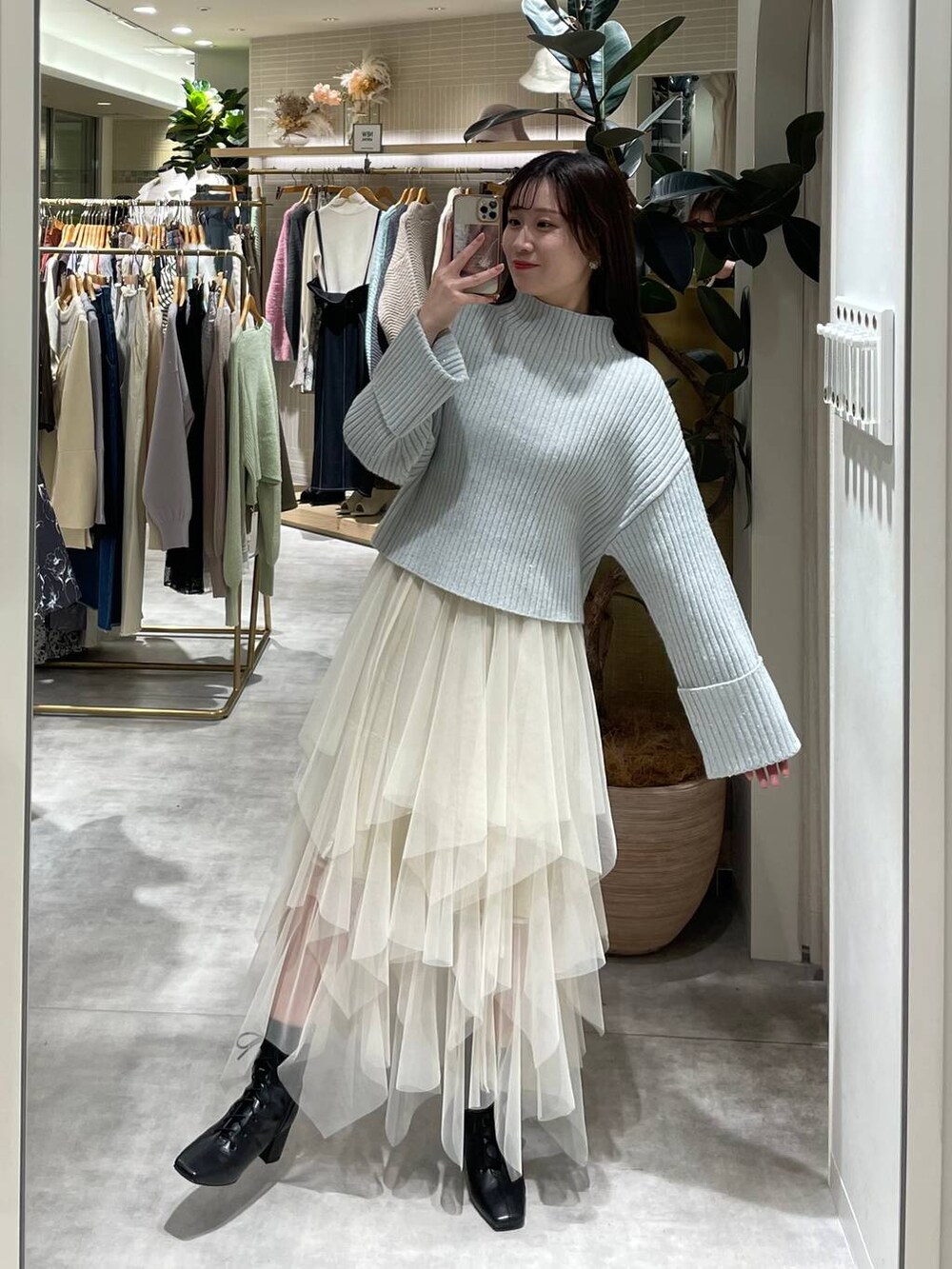 ブラック系のブーツ、ブルー系のニット/セーター、ホワイト系のスカートを着用したレディースの冬コーディネートの3枚目の写真