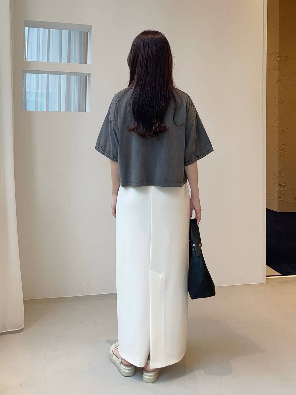 ブラック系のショルダーバッグ、グレー系のTシャツ/カットソー、ホワイト系のスカートを着用したレディースの夏コーディネートの2枚目の写真