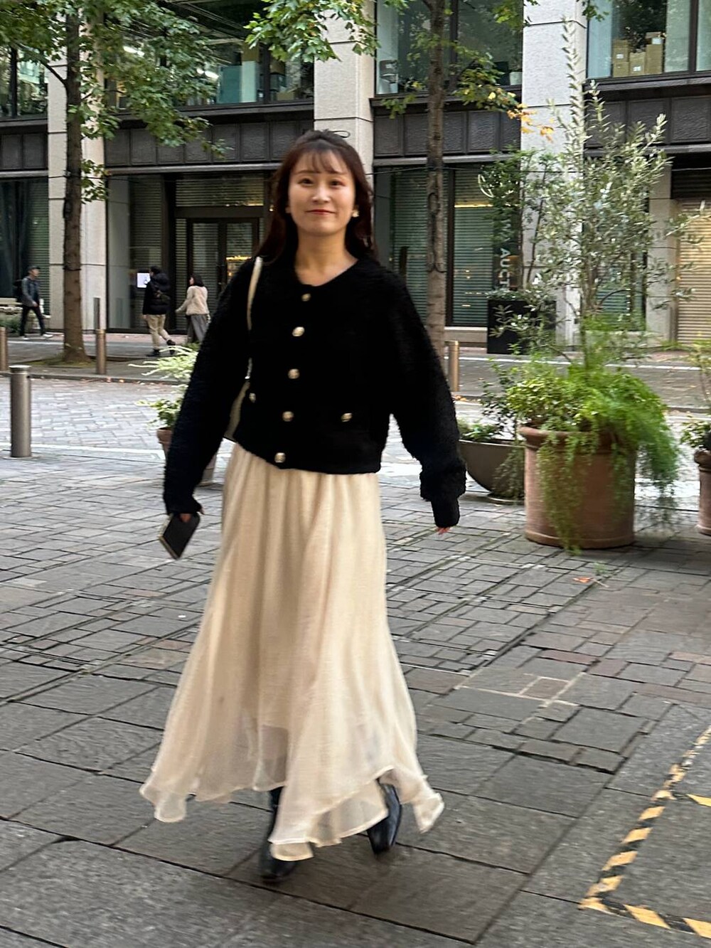 ブラック系のカーディガン/ボレロ、ホワイト系のスカートを着用したレディースの秋コーディネートの8枚目の写真