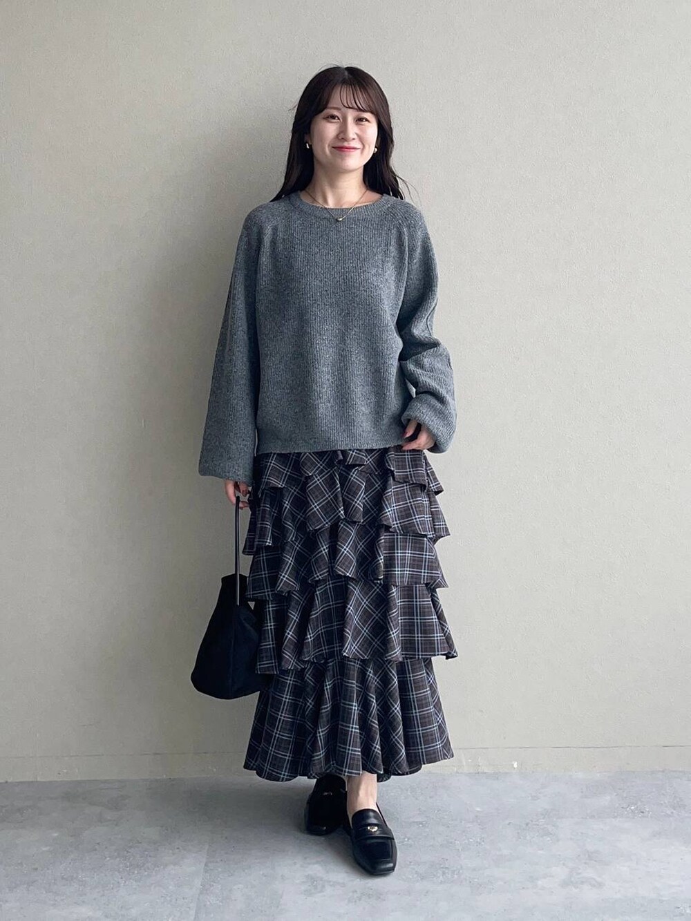 グレー系のニット/セーター、ブラウン系のスカート、ブラック系のローファーを着用したレディースの秋コーディネートの3枚目の写真