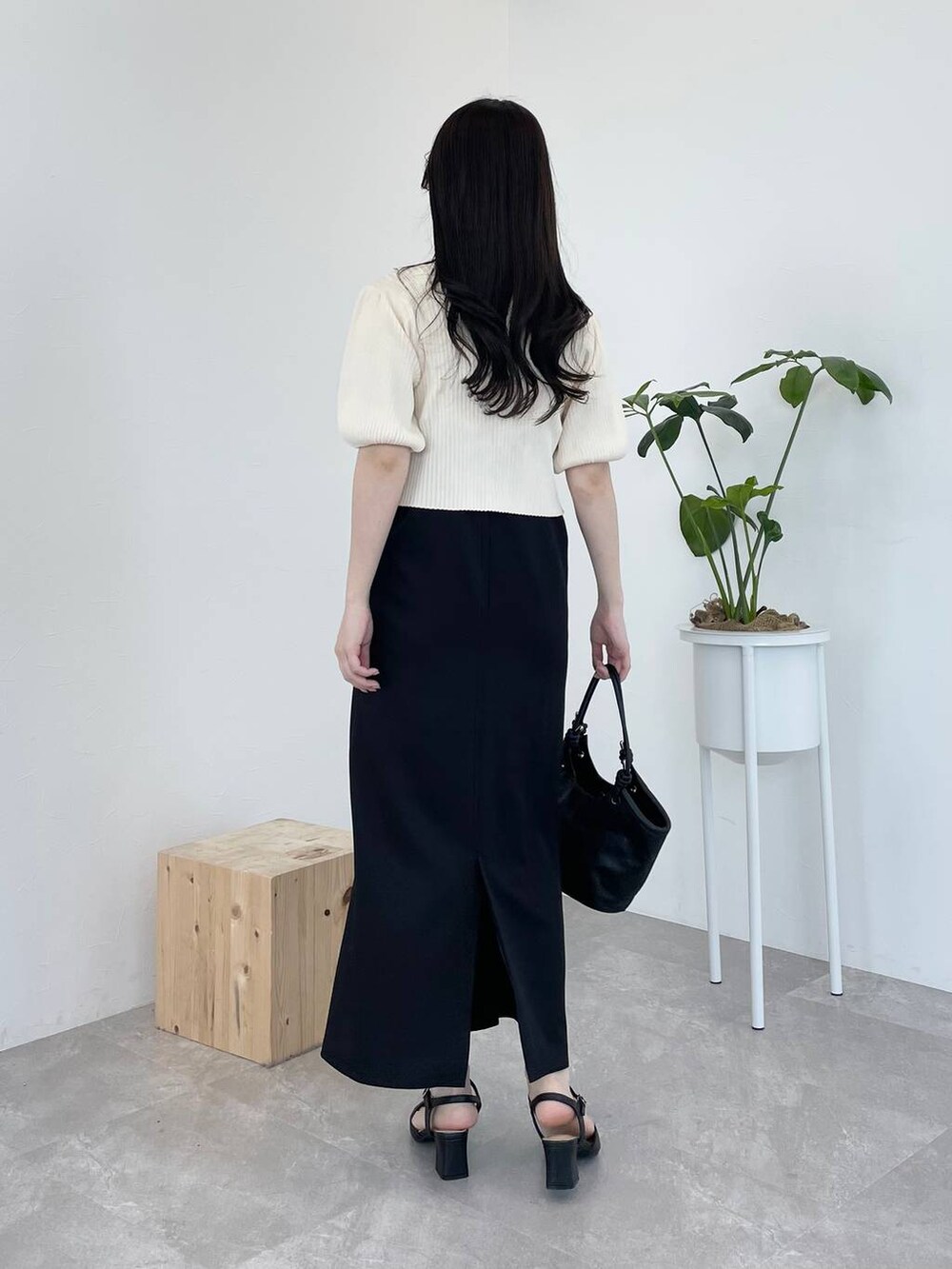 ブラック系のドレス、ブラック系のハンドバッグ、ブラック系のパンプスを着用したレディースの春コーディネートの2枚目の写真