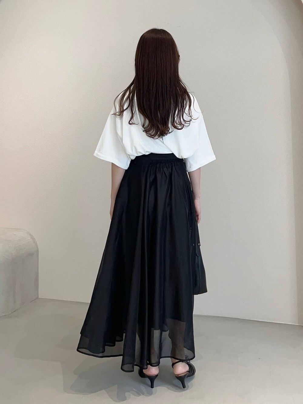 ブラック系のショルダーバッグ、ブラック系のパンプス、ホワイト系のTシャツ/カットソーを着用したレディースの夏コーディネートの2枚目の写真