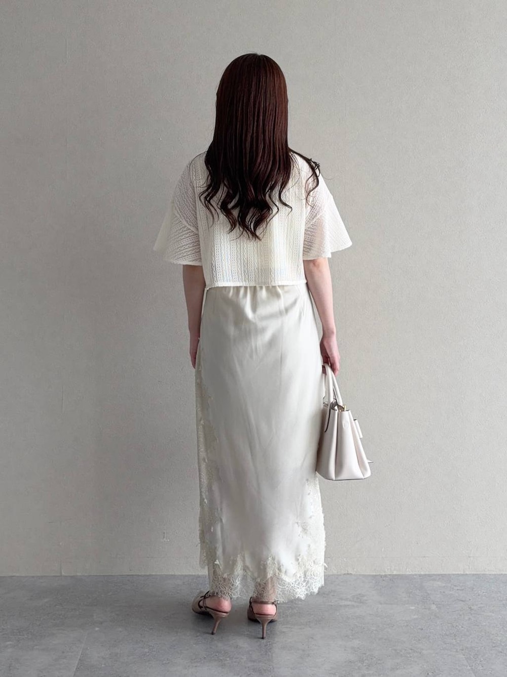 ホワイト系のアンサンブル、ブラウン系のサンダル、ホワイト系のスカートを着用したレディースの夏コーディネートの4枚目の写真