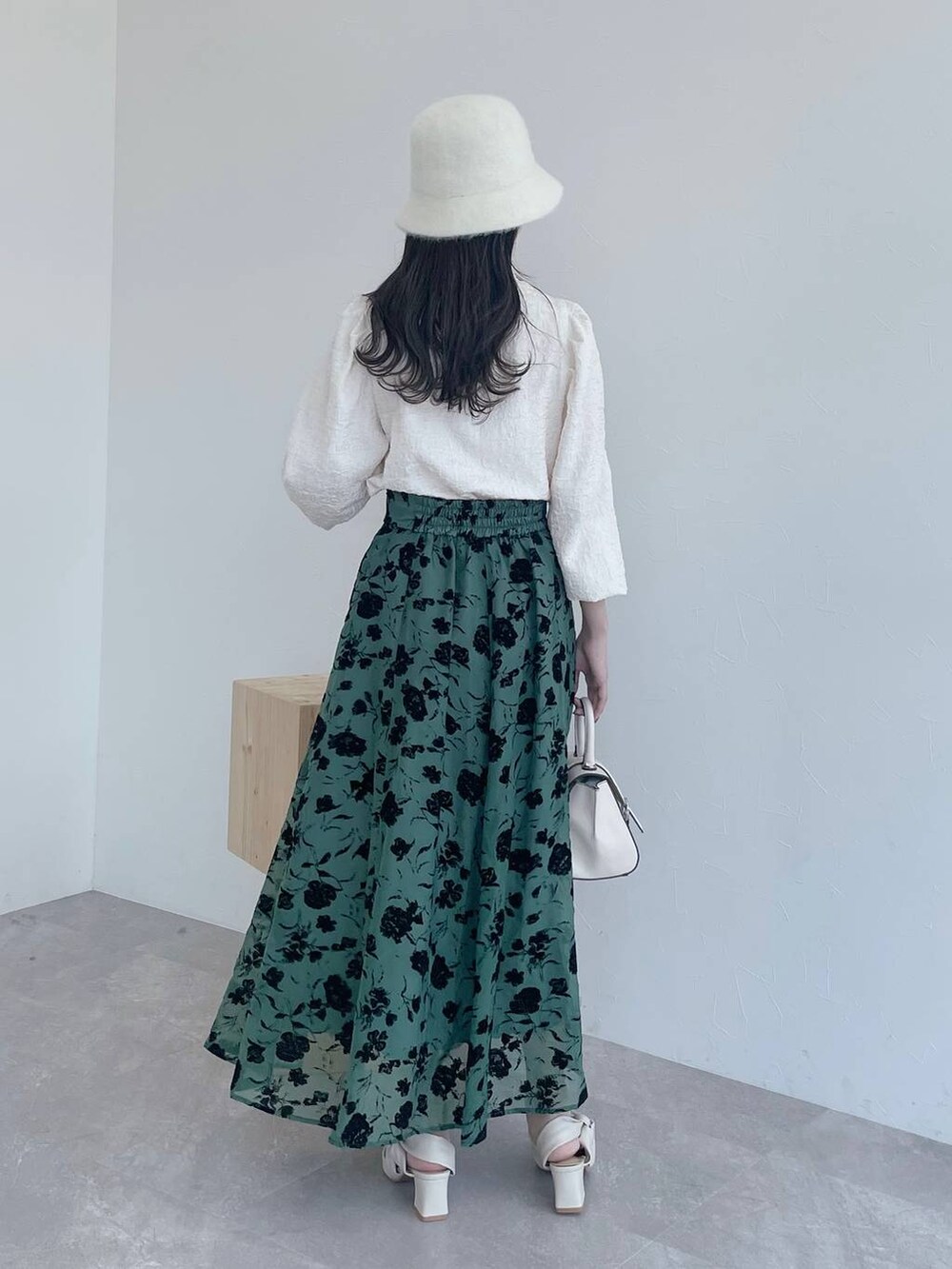 ホワイト系のハンドバッグ、ベージュ系のスカート、ホワイト系のパンプスを着用したレディースの夏コーディネートの2枚目の写真