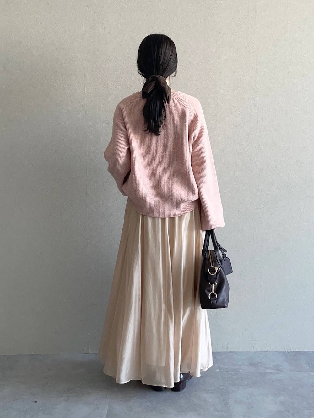 ピンク系のニット/セーター、ブラウン系のボストンバッグ、ベージュ系のスカートを着用したレディースの冬コーディネートの2枚目の写真
