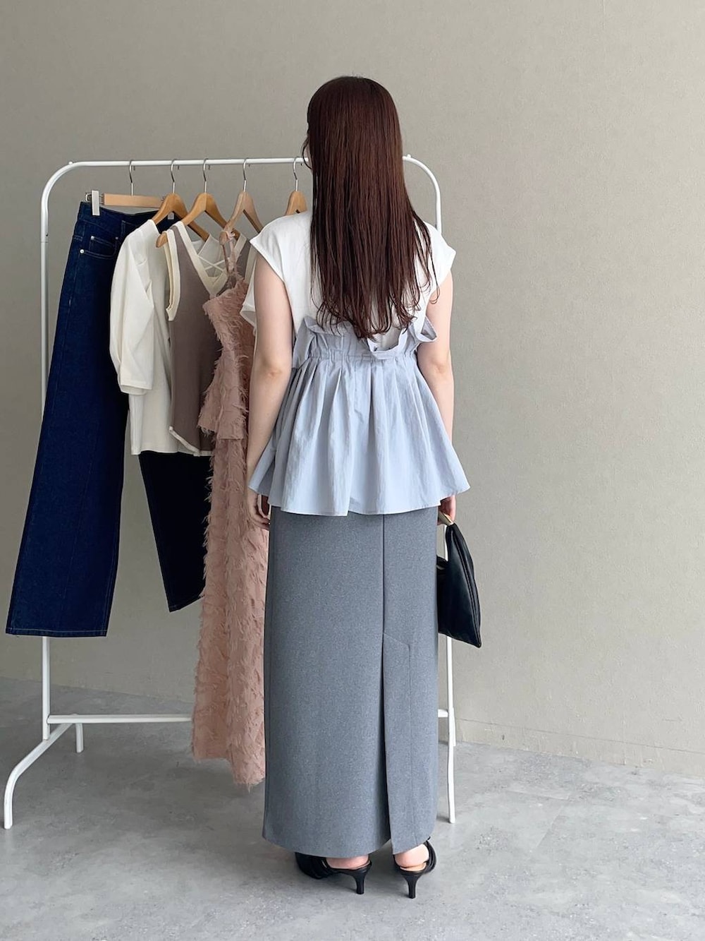 ブラック系のパンプス、ブラック系のハンドバッグ、グレー系のTシャツ/カットソーを着用したレディースの夏コーディネートの2枚目の写真