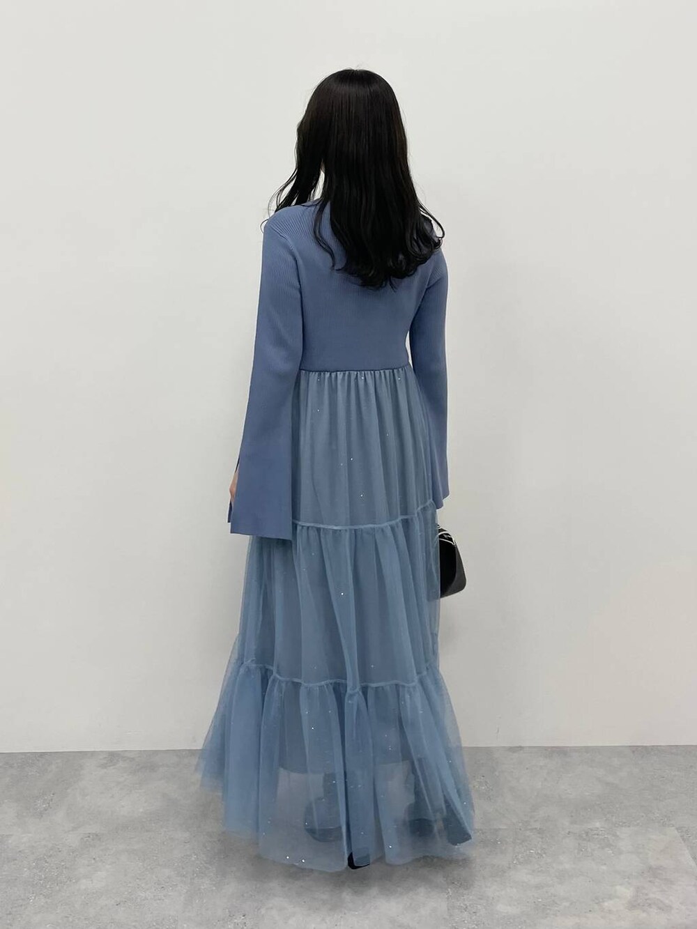 ブラック系のハンドバッグ、ブラック系のブーツ、ブルー系のワンピースを着用したレディースの秋コーディネートの2枚目の写真