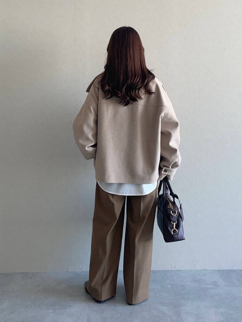 ベージュ系のピーコート、ベージュ系のニット/セーター、ブラウン系のボストンバッグを着用したレディースの冬コーディネートの2枚目の写真