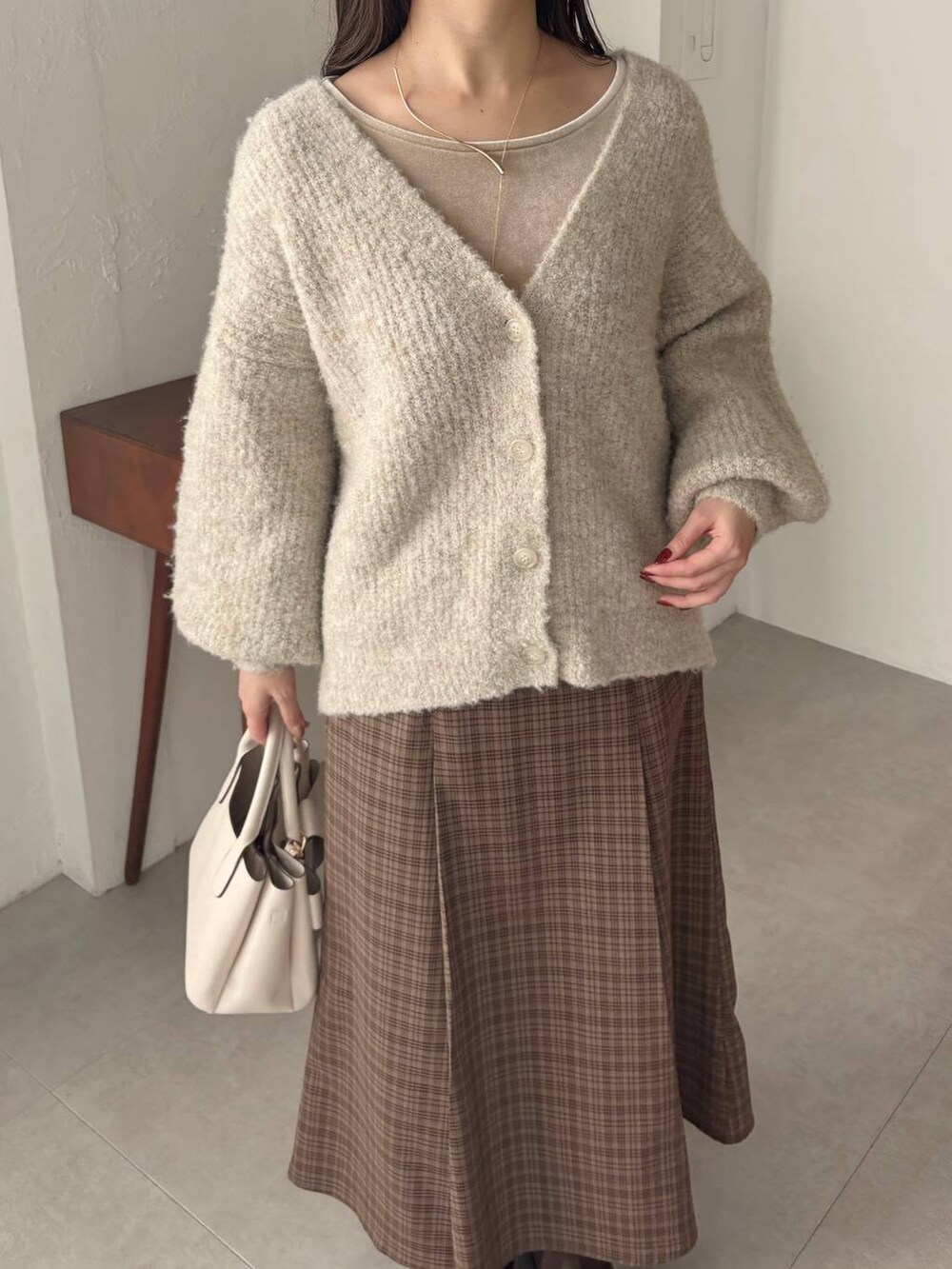 ブラウン系のブーツ、ブラウン系のスカート、ベージュ系のTシャツ/カットソーを着用したレディースの冬コーディネートの4枚目の写真