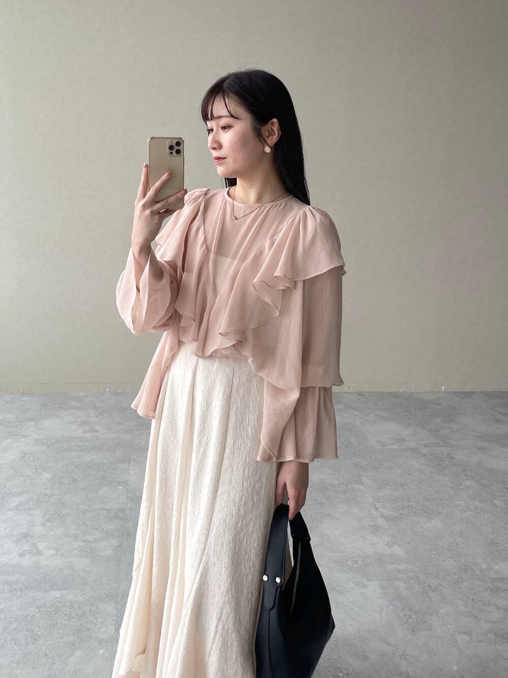 ホワイト系のスカート、ブラック系のローファー、ホワイト系のショルダーバッグを着用したレディースの春コーディネートの3枚目の写真