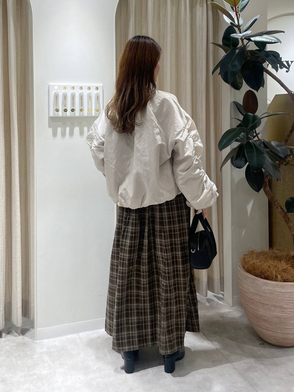 ブラック系のボストンバッグ、ブラック系のブーツ、ホワイト系のブルゾンを着用したレディースの秋コーディネートの2枚目の写真