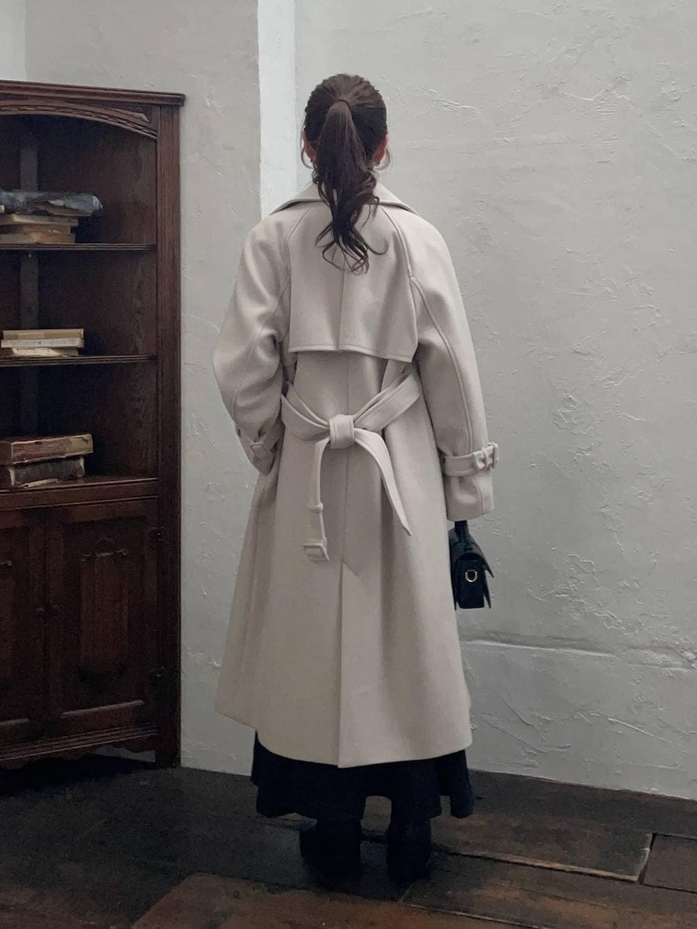 ホワイト系のチェスターコート、ブラック系のブーツ、ブラック系のショルダーバッグを着用したレディースの冬コーディネートの2枚目の写真