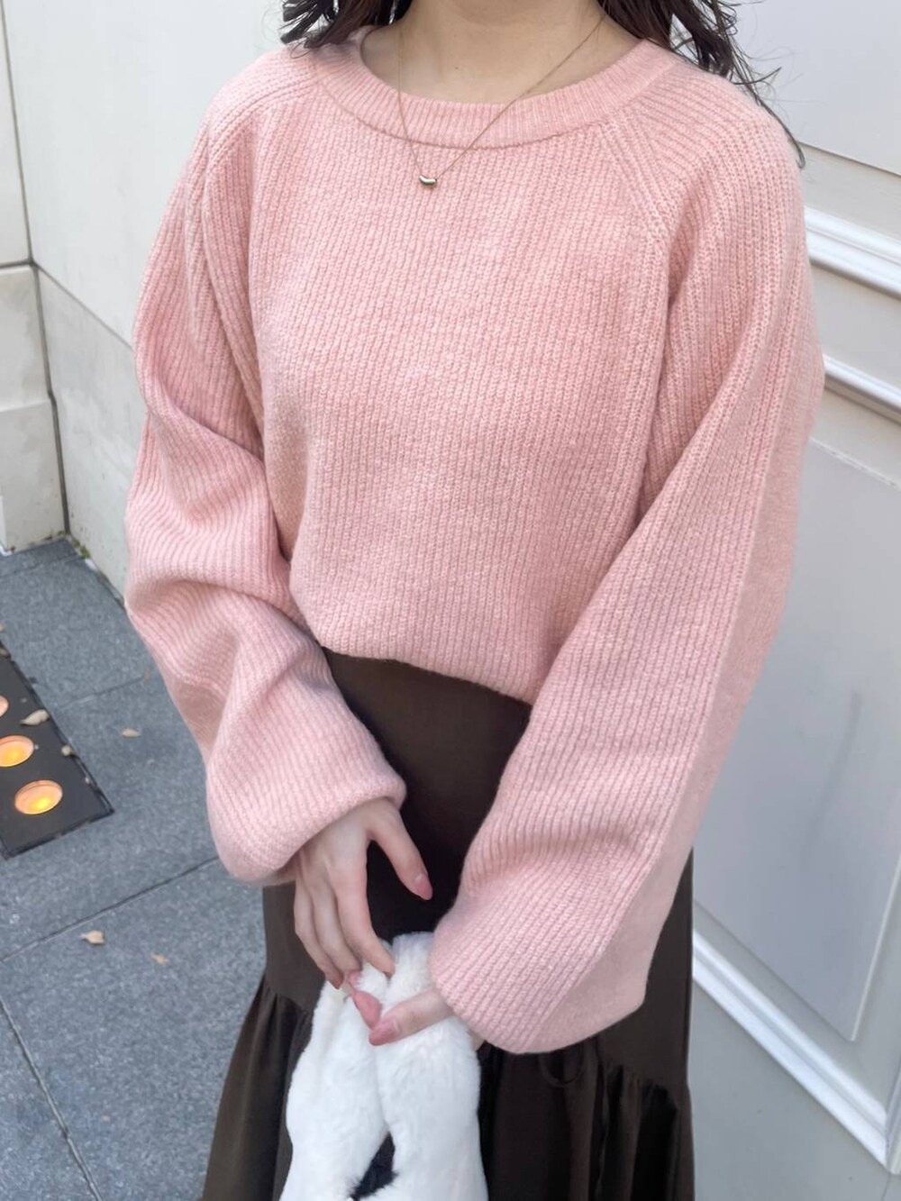 ピンク系のニット/セーター、ホワイト系のハンドバッグ、ブラウン系のスカートを着用したレディースの冬コーディネートの3枚目の写真