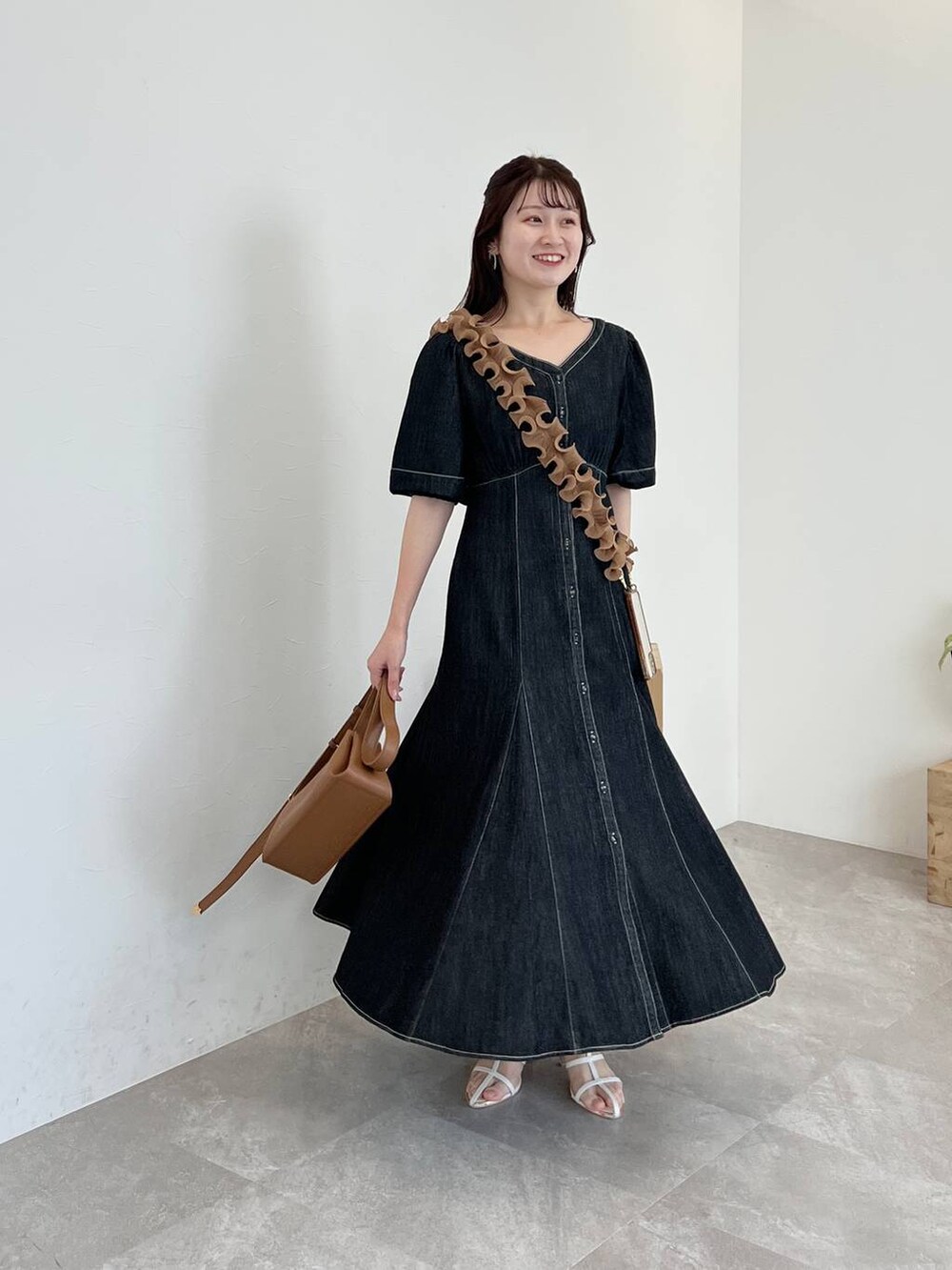 ブラウン系のショルダーバッグ、ブラック系のワンピース、ホワイト系のサンダルを着用したレディースの春コーディネートの4枚目の写真