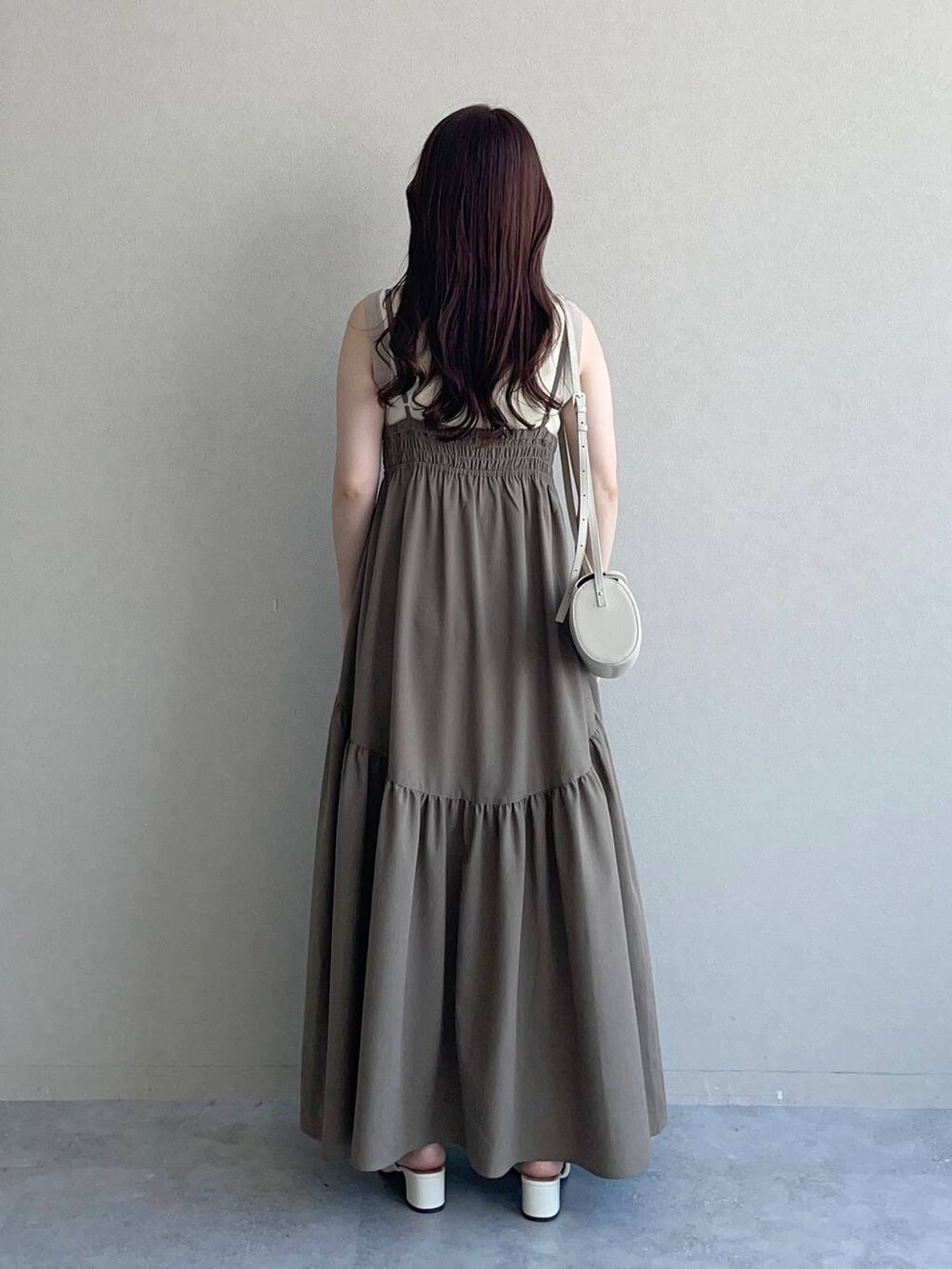 ホワイト系のタンクトップ、ホワイト系のショルダーバッグ、ブラウン系のワンピースを着用したレディースの夏コーディネートの2枚目の写真