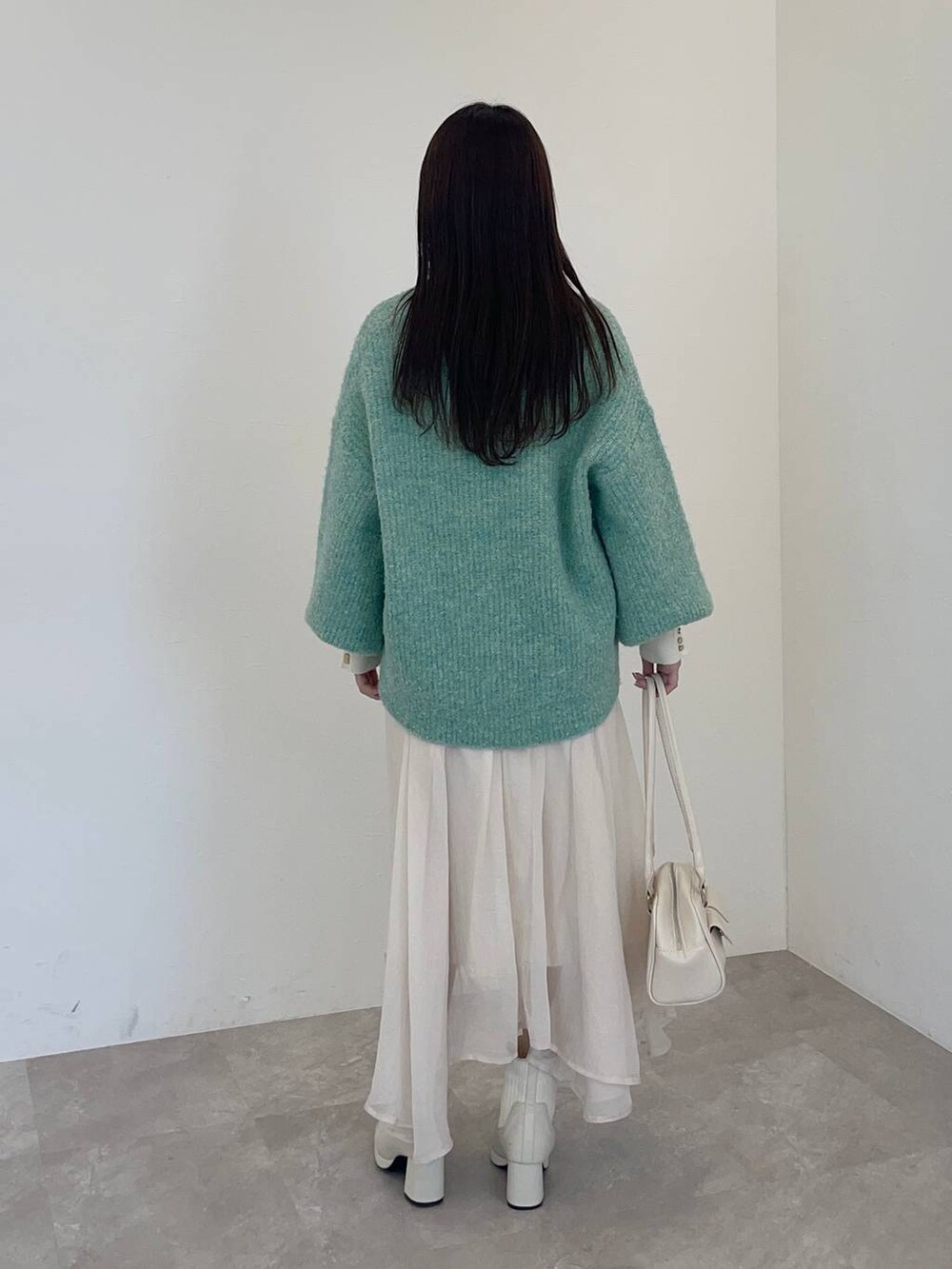 ホワイト系のブーツ、ホワイト系のニット/セーター、グリーン系のカーディガン/ボレロを着用したレディースの冬コーディネートの2枚目の写真