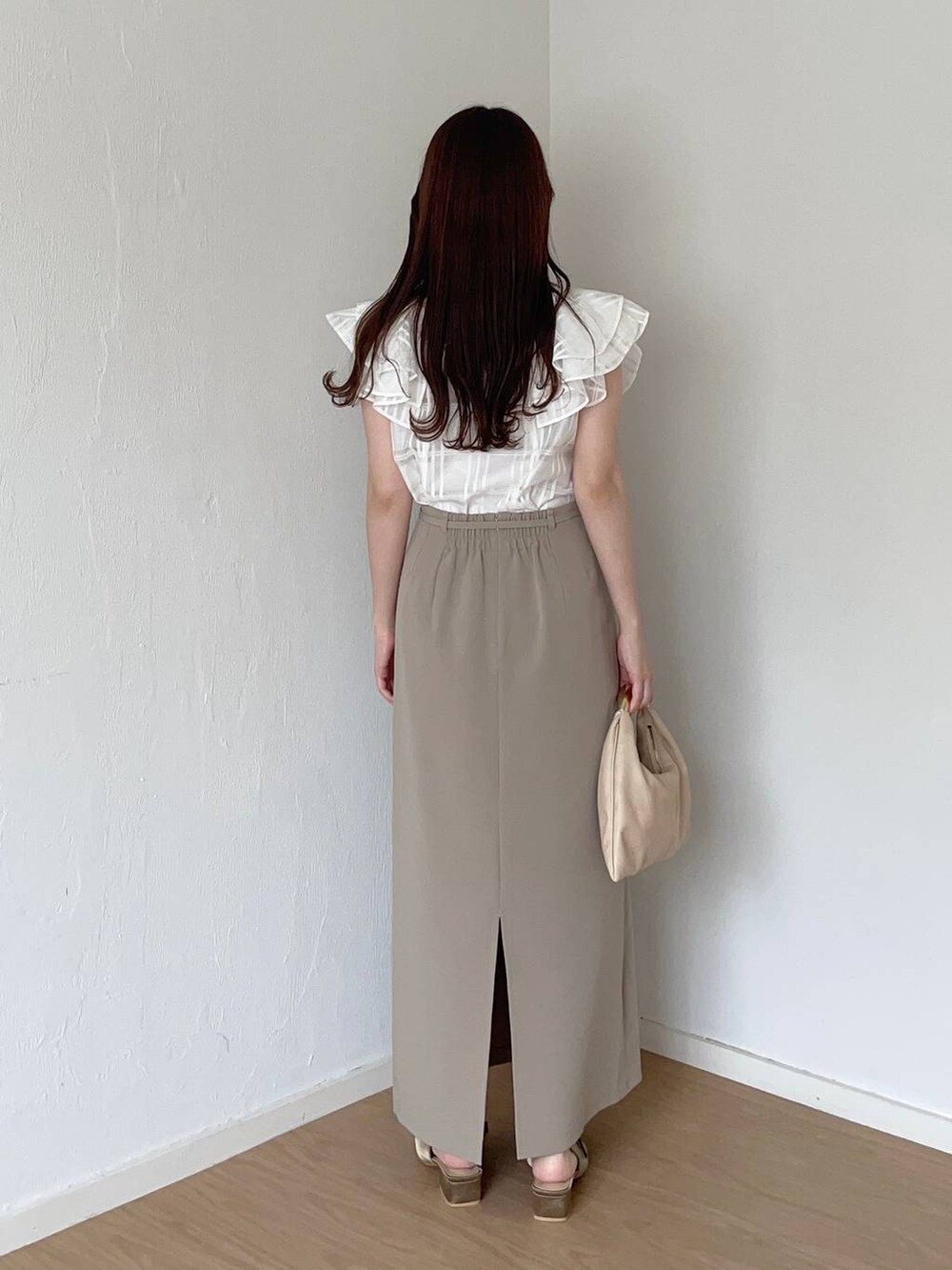 ブラウン系のサンダル、ベージュ系のハンドバッグ、ベージュ系のスカートを着用したレディースの秋コーディネートの2枚目の写真