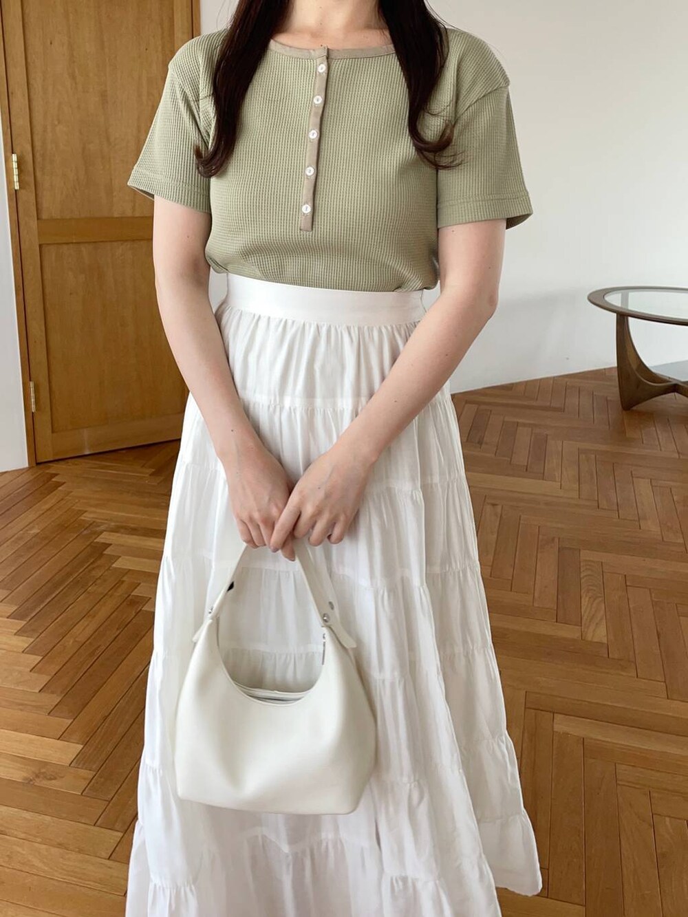 ホワイト系のショルダーバッグ、ゴールド系のパンプス、グリーン系のTシャツ/カットソーを着用したレディースの夏コーディネートの3枚目の写真