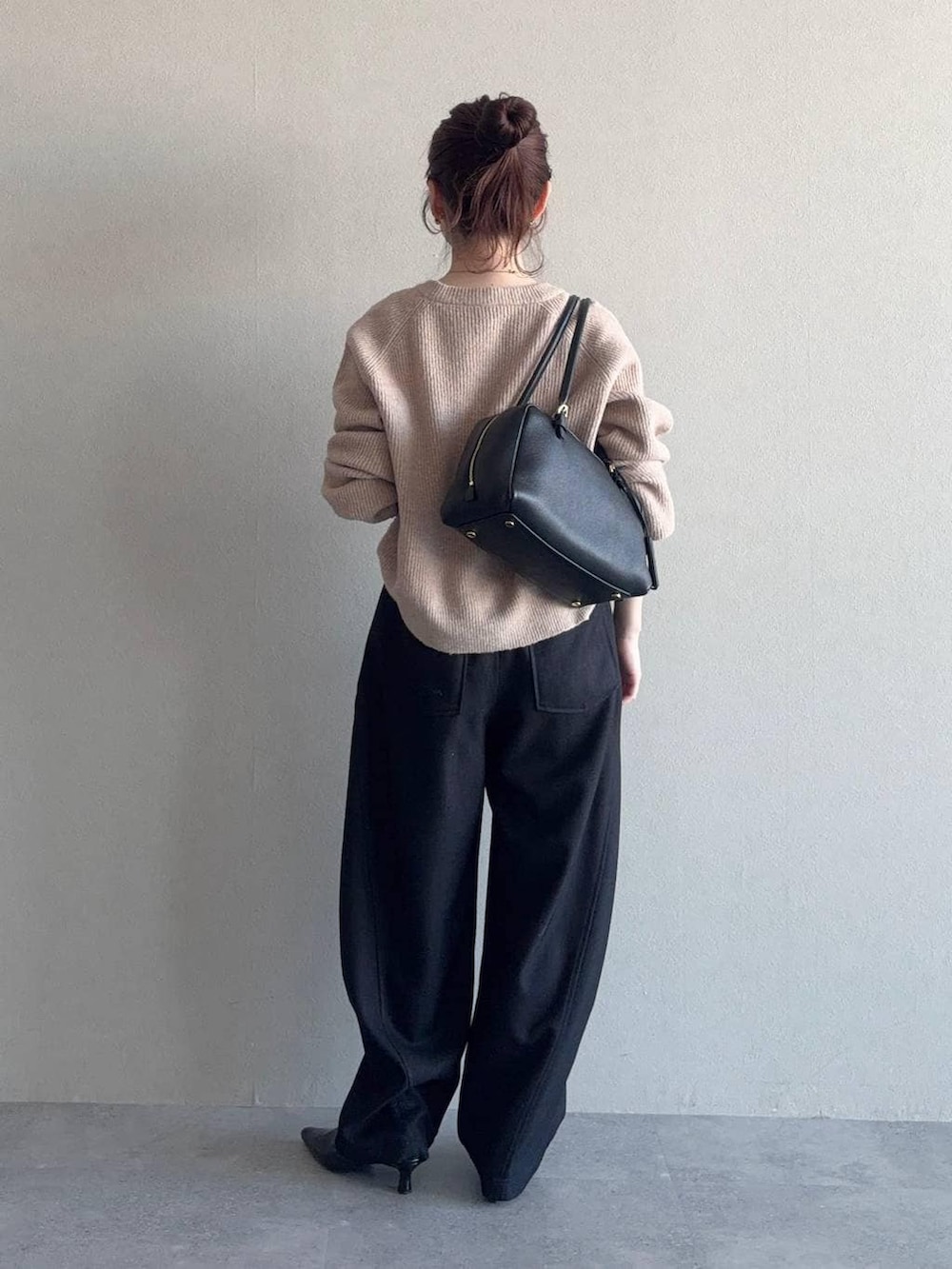 ベージュ系のニット/セーター、ブラック系のハンドバッグ、ブラック系のサンダルを着用したレディースの冬コーディネートの2枚目の写真