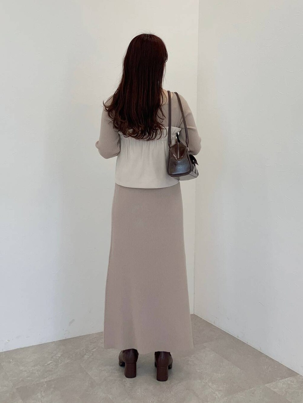 ブラウン系のブーツ、ブラウン系のハンドバッグ、ホワイト系のスカートを着用したレディースの冬コーディネートの2枚目の写真