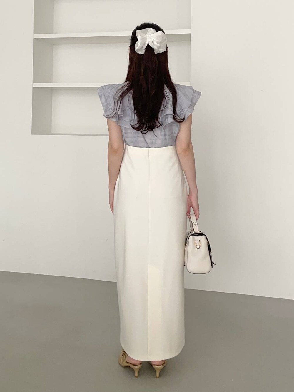 ゴールド系のパンプス、ホワイト系のショルダーバッグ、ブルー系のシャツ/ブラウスを着用したレディースの夏コーディネートの2枚目の写真