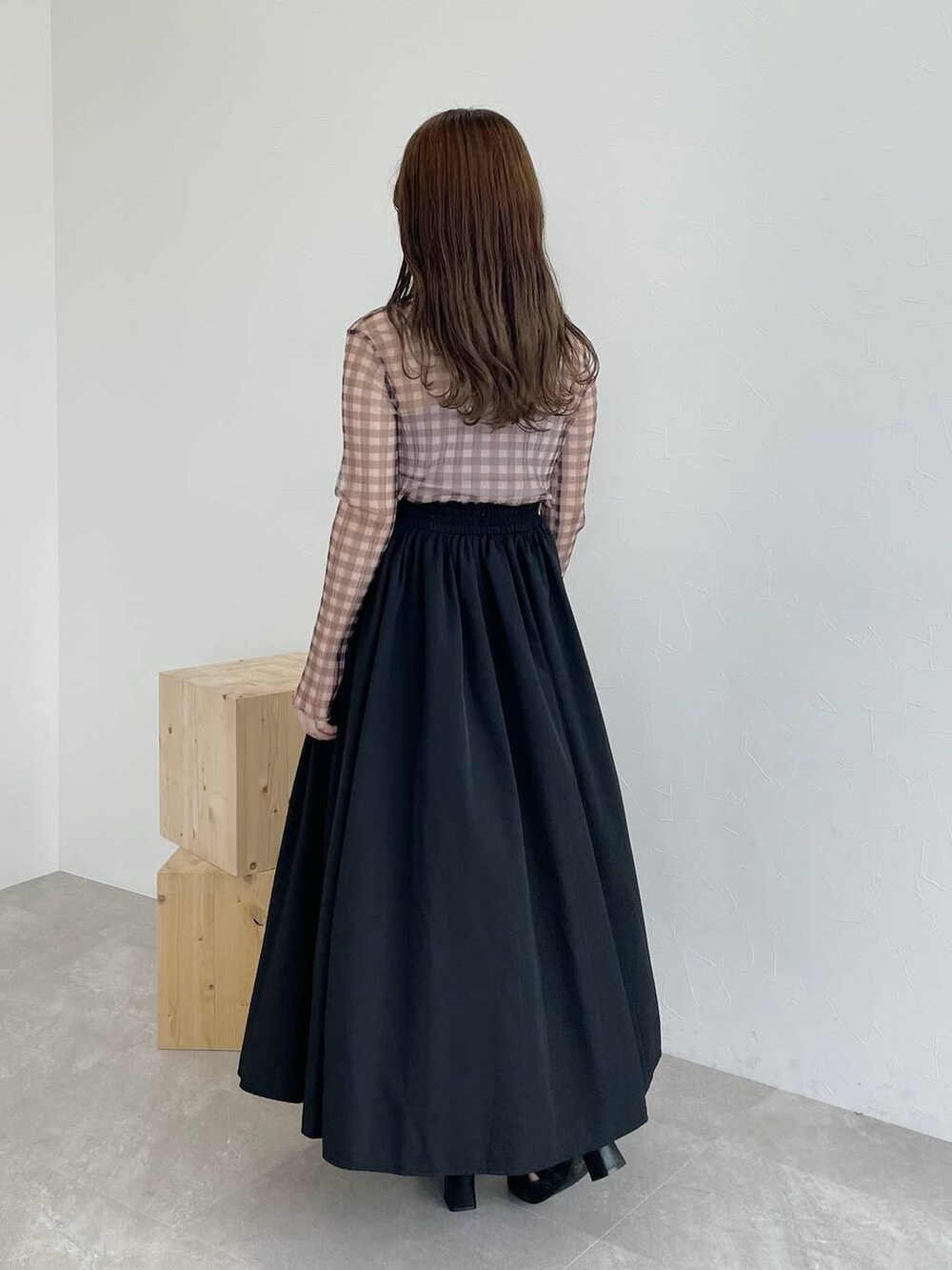 ブラック系のスカート、ブラウン系のハンドバッグ、ブラック系のパンプスを着用したレディースの秋コーディネートの2枚目の写真