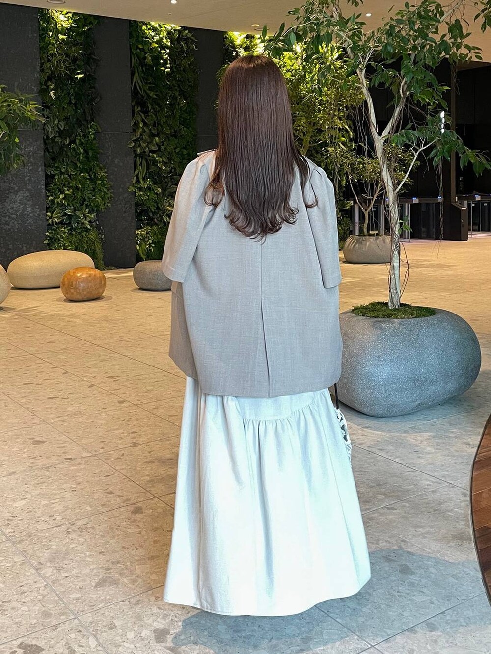 ベージュ系のテーラードジャケット、ベージュ系のワンピース、ブラック系のスリッポンを着用したレディースの夏コーディネートの2枚目の写真